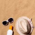 Op het strand met een zonnebril, zonnehoed en zonnebrandcreme